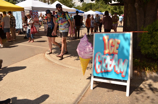 Attendees passing by booths and conversing with one another on their way to the main stage where the musical performances are held, Spruce Pine, Aug. 30. 