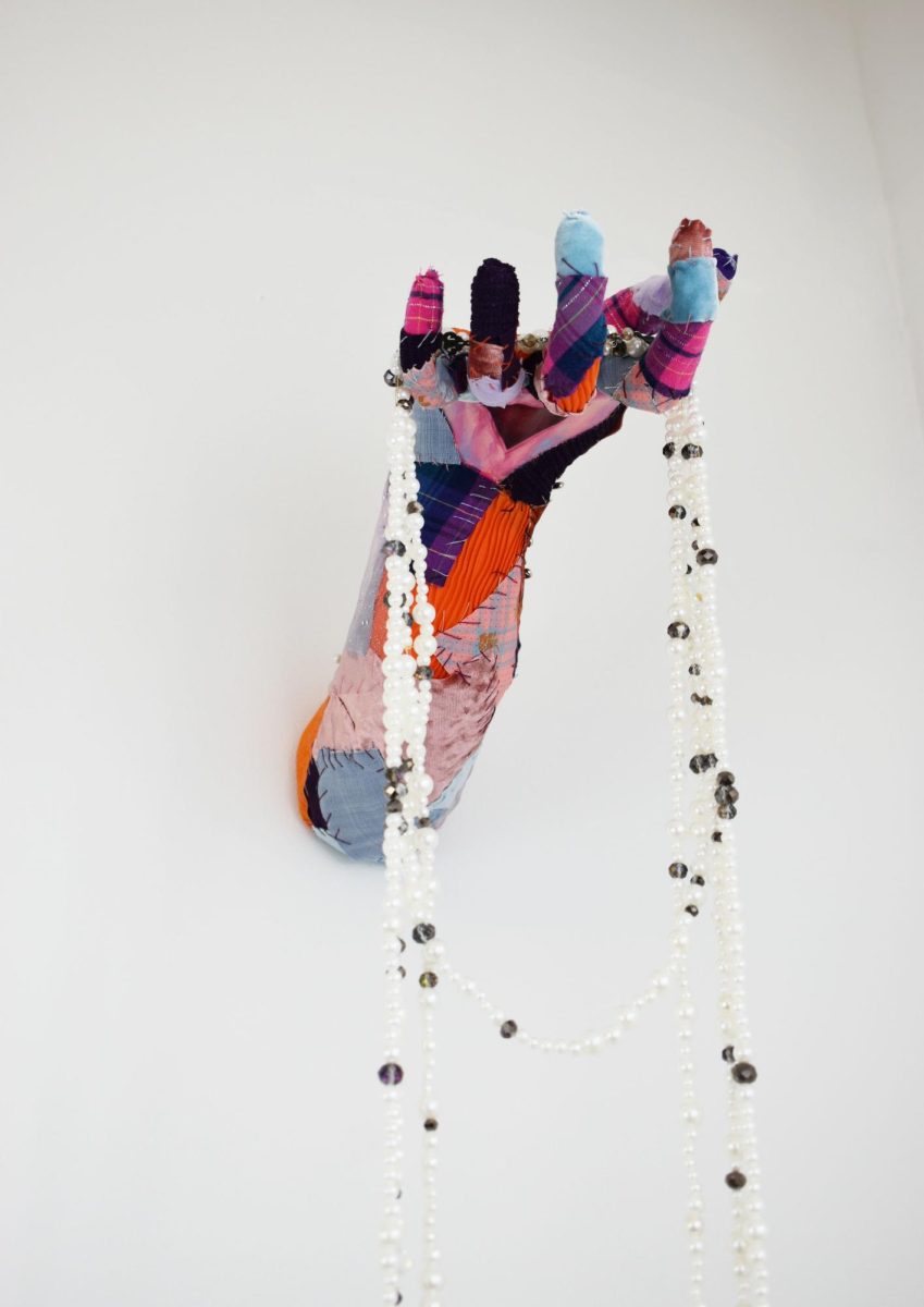 In the shape of a hand, this fabric art piece, “If I give this to you, will you wield it kindly?” is included in the collection “Sewing Lavender” by artist Toni Martinez.