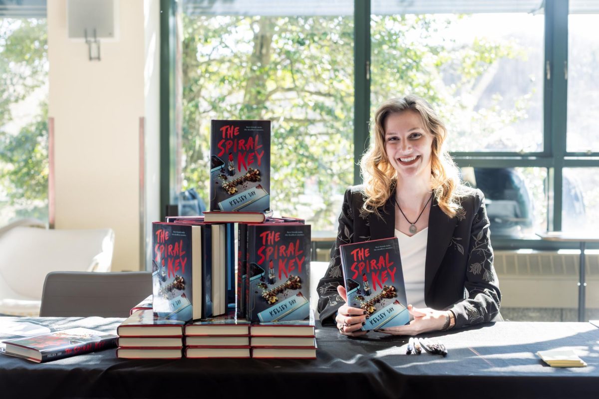 Author Kelsey Day sits in Summit Trail Solarium surrounded by their debut novel, “The Spiral Key,” on March 24. “The Spiral Key” mixes elements of thriller, virtual reality and adolescent friendships with a dramatic twist.