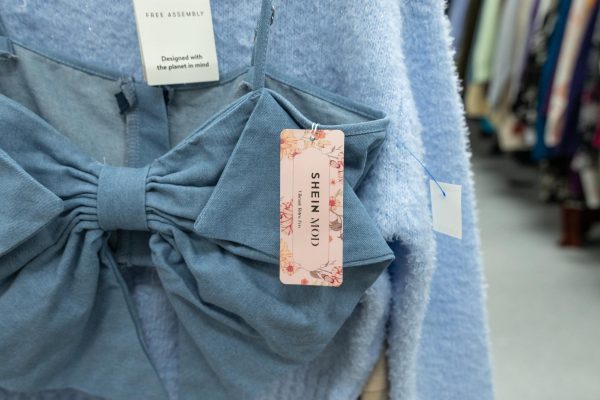 A top from Shein with the tag still attached hangs in Goodwill on April 2. A tag behind it reads "Designed with the planet in mind." 